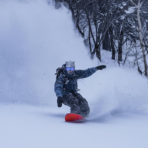 snowboarder riding through powder